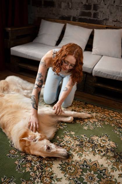 La maîtresse d'un chien couché sur le sol procède à des techniques de massage pour réduire le stress.
